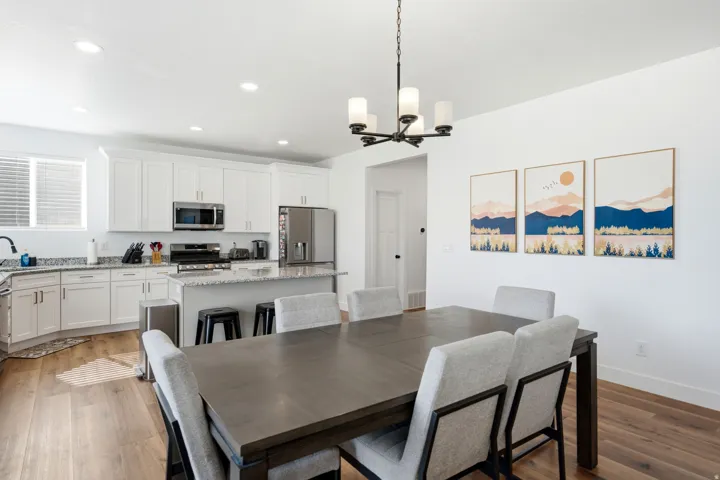 Open-concept kitchen and dining area featuring wood-finish flooring, recessed lighting, and a contemporary chandelier