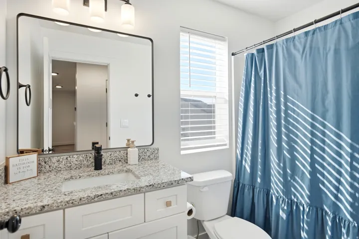 Bathroom featuring a white vanity with a speckled countertop, a rectangular sink, and a black faucet