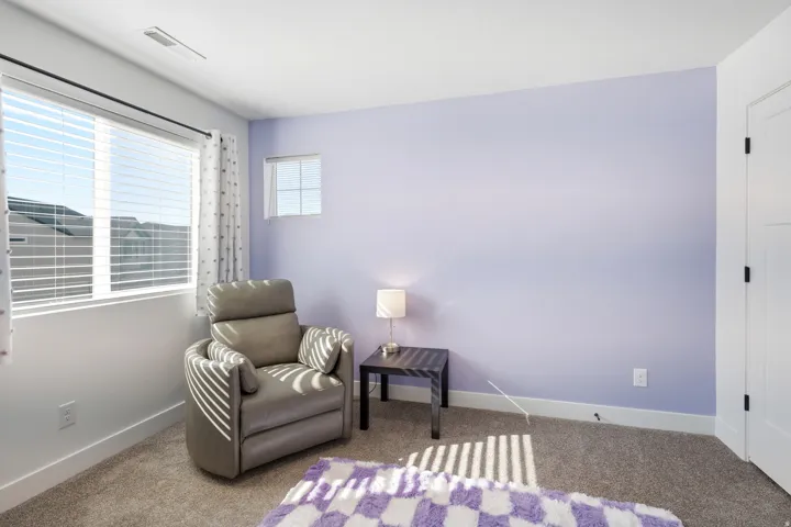 Carpeted room featuring a large window with blinds, a smaller window, and a door with matte black hardware
