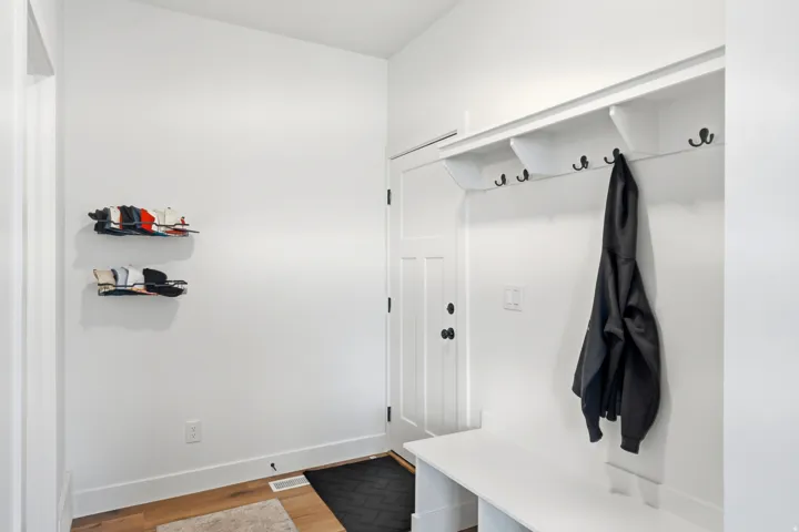 Entryway featuring a built-in bench, overhead shelving with cubbies, and multiple coat hooks