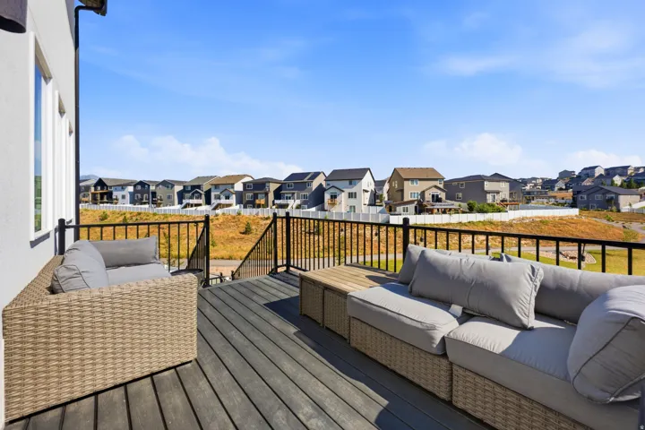 Outdoor deck featuring composite decking, black metal railings, and a white stucco exterior