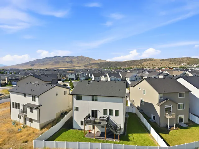 Expansive backyard featuring a manicured lawn, white vinyl fencing, and a multi-level deck with black railings
