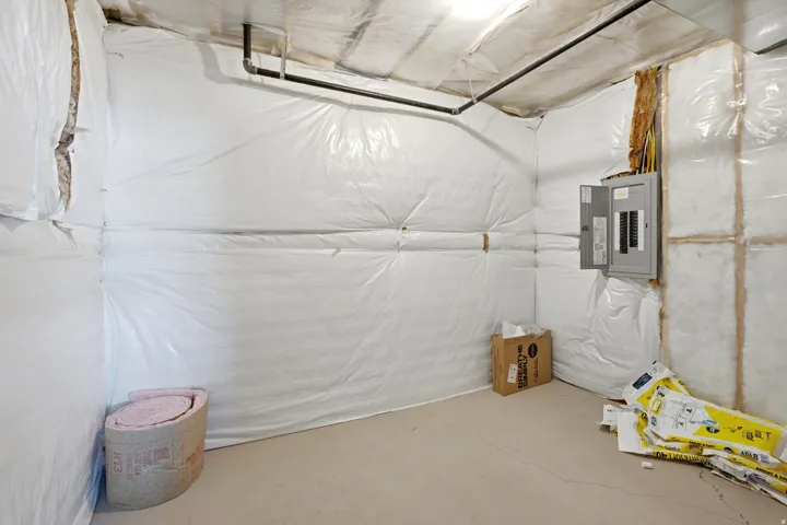 Unfinished basement area featuring insulated walls, concrete flooring, and an exposed electrical panel