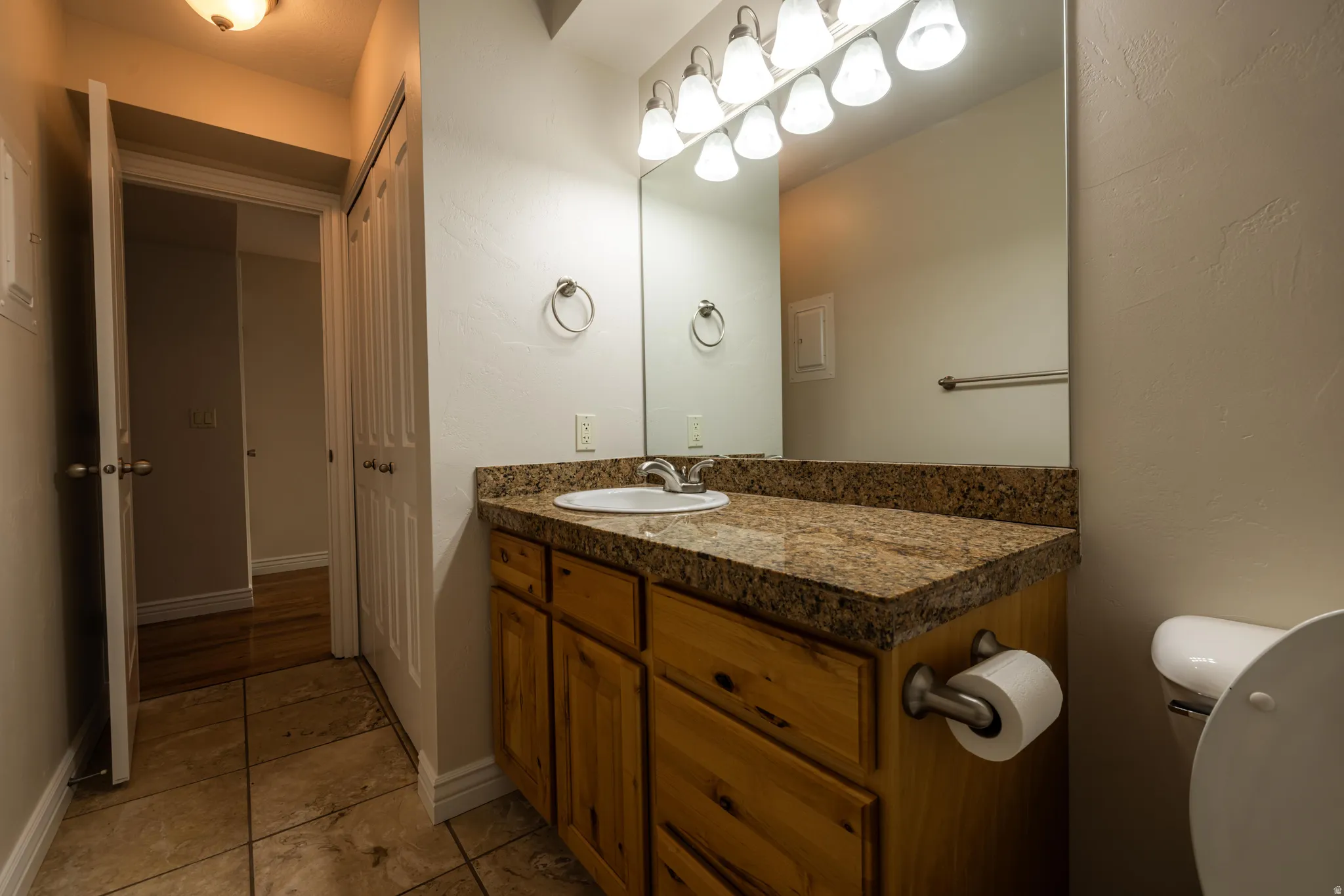 Bathroom vanity featuring a light wood-finish cabinet, stone countertop, and integrated sink