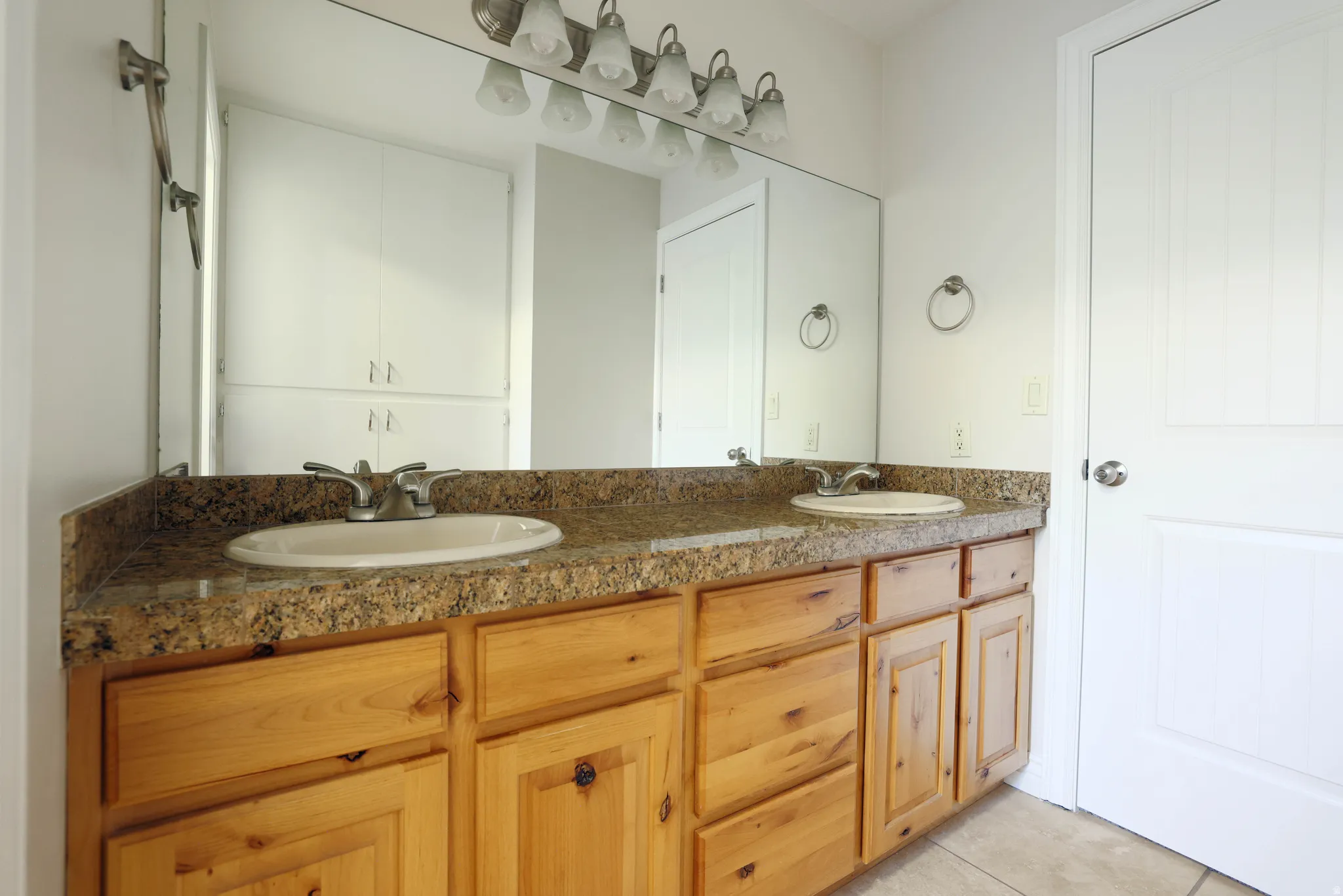 Double vanity featuring wood cabinetry, granite-look countertop, and dual undermount sinks