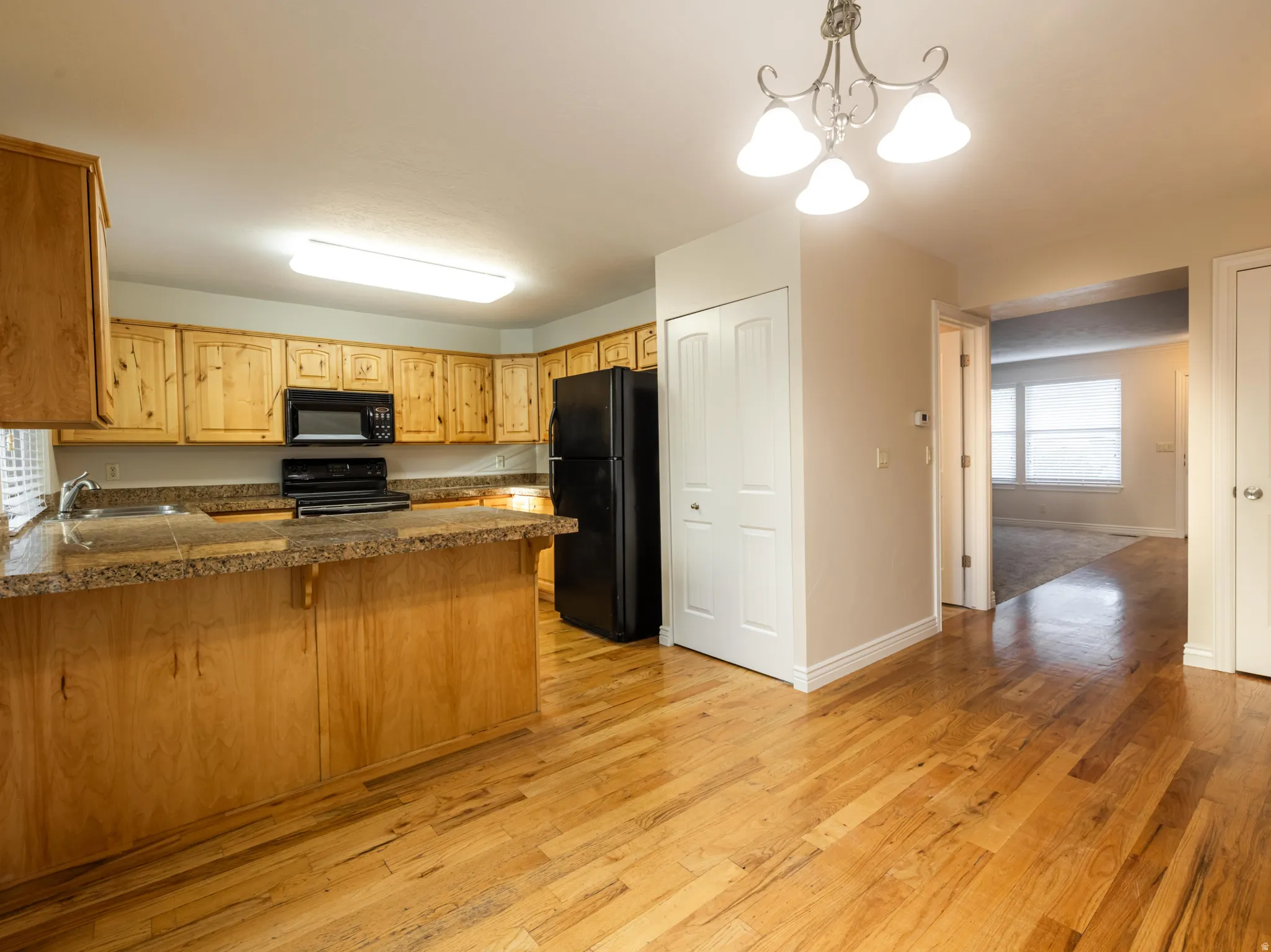 Kitchen featuring wood cabinetry, granite-look countertops, and wood-finish flooring