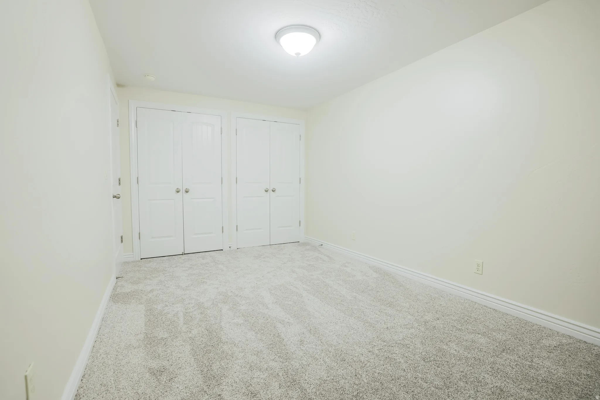 Neutral wall colors, light-toned carpet, and a flush mount ceiling light fixture