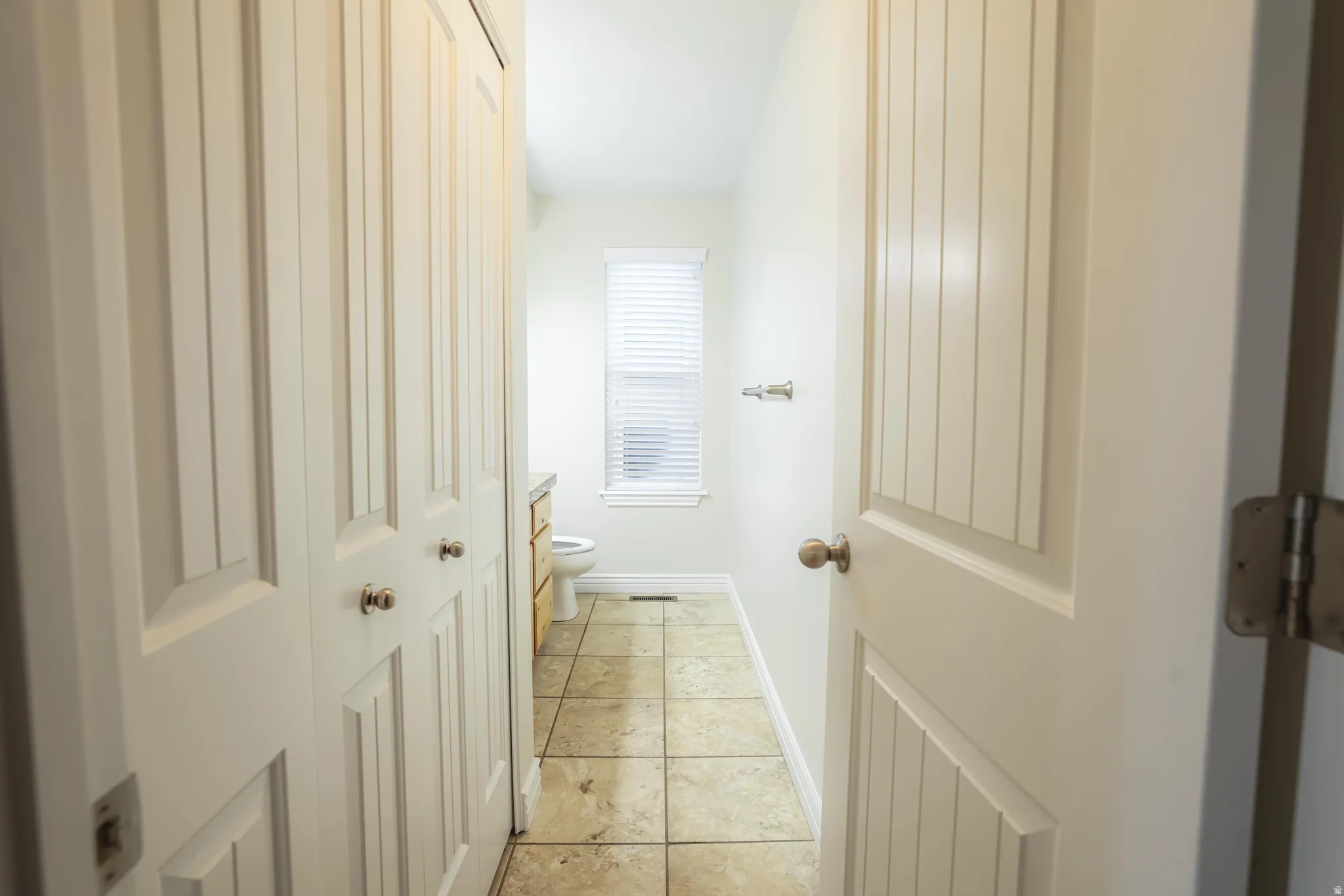 Half-bath featuring white bi-fold closet doors, tile flooring, and light-colored walls