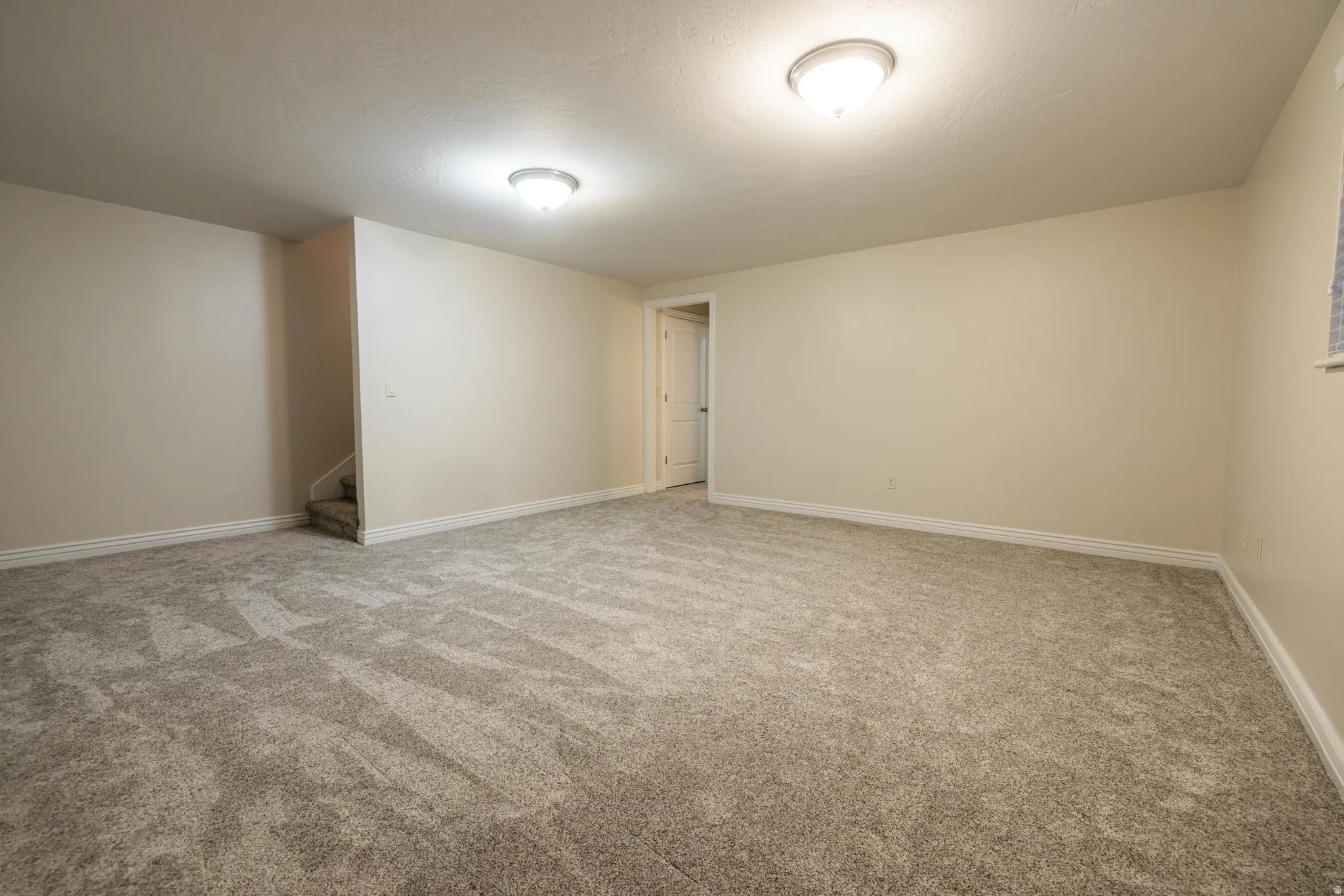 Spacious family room featuring neutral carpeting, light-toned walls, and white baseboards