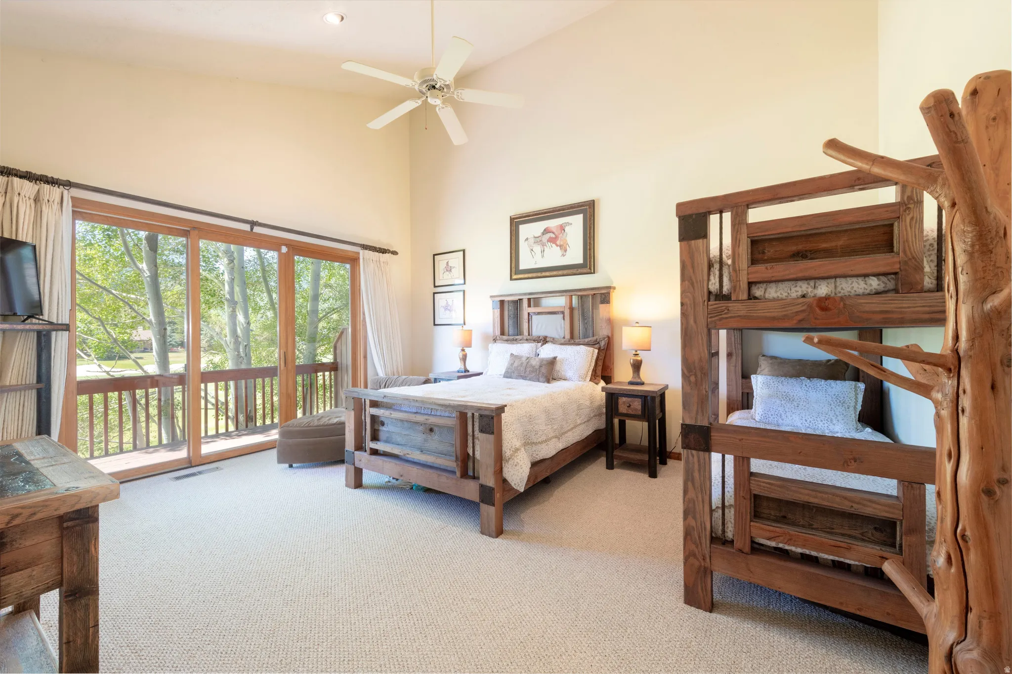 Vaulted ceiling bedroom with light-toned carpet flooring and a ceiling fan