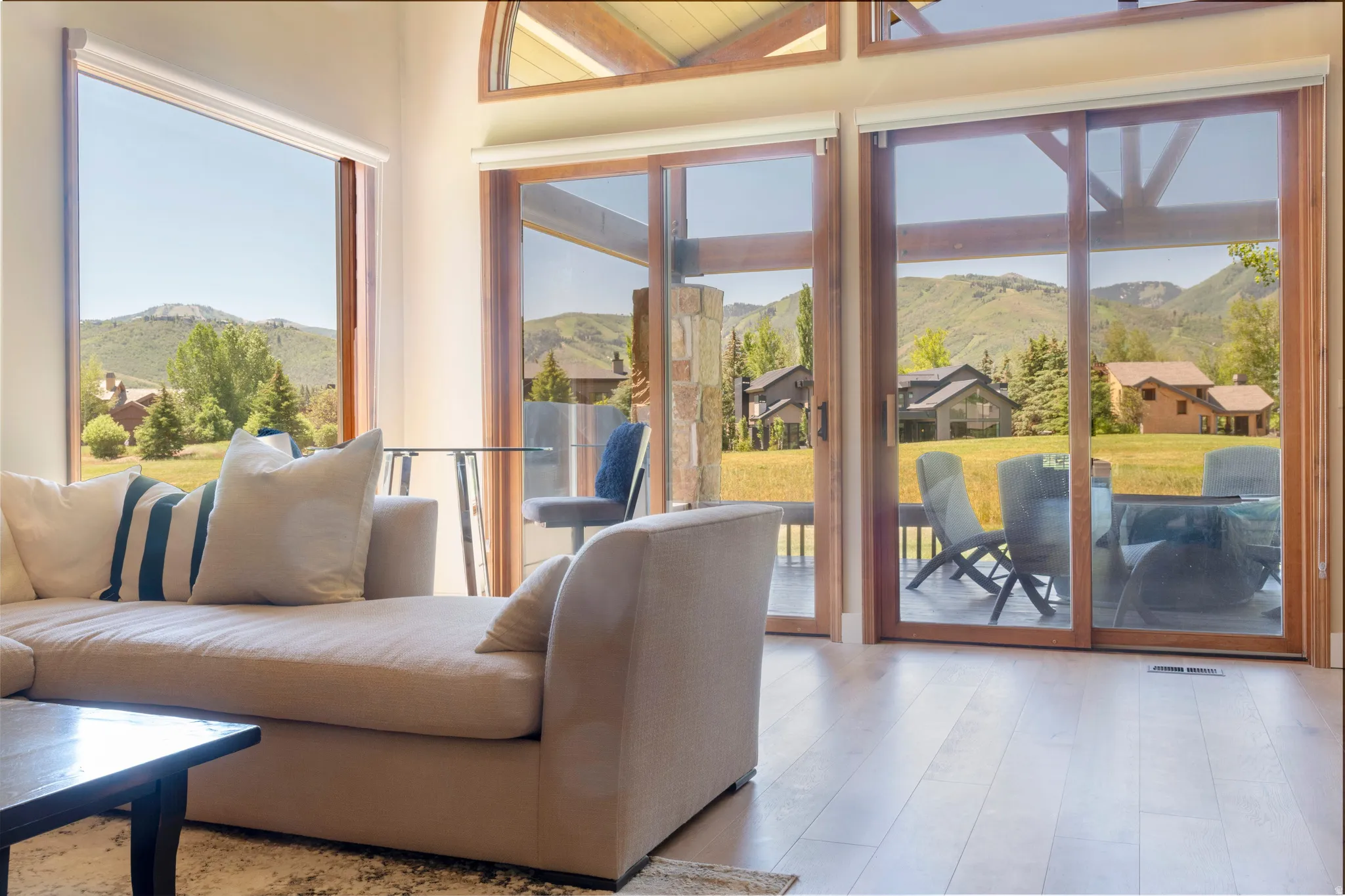 Wood-finish flooring extending to expansive sliding glass doors and a large picture window, offering abundant natural light and exterior scenery