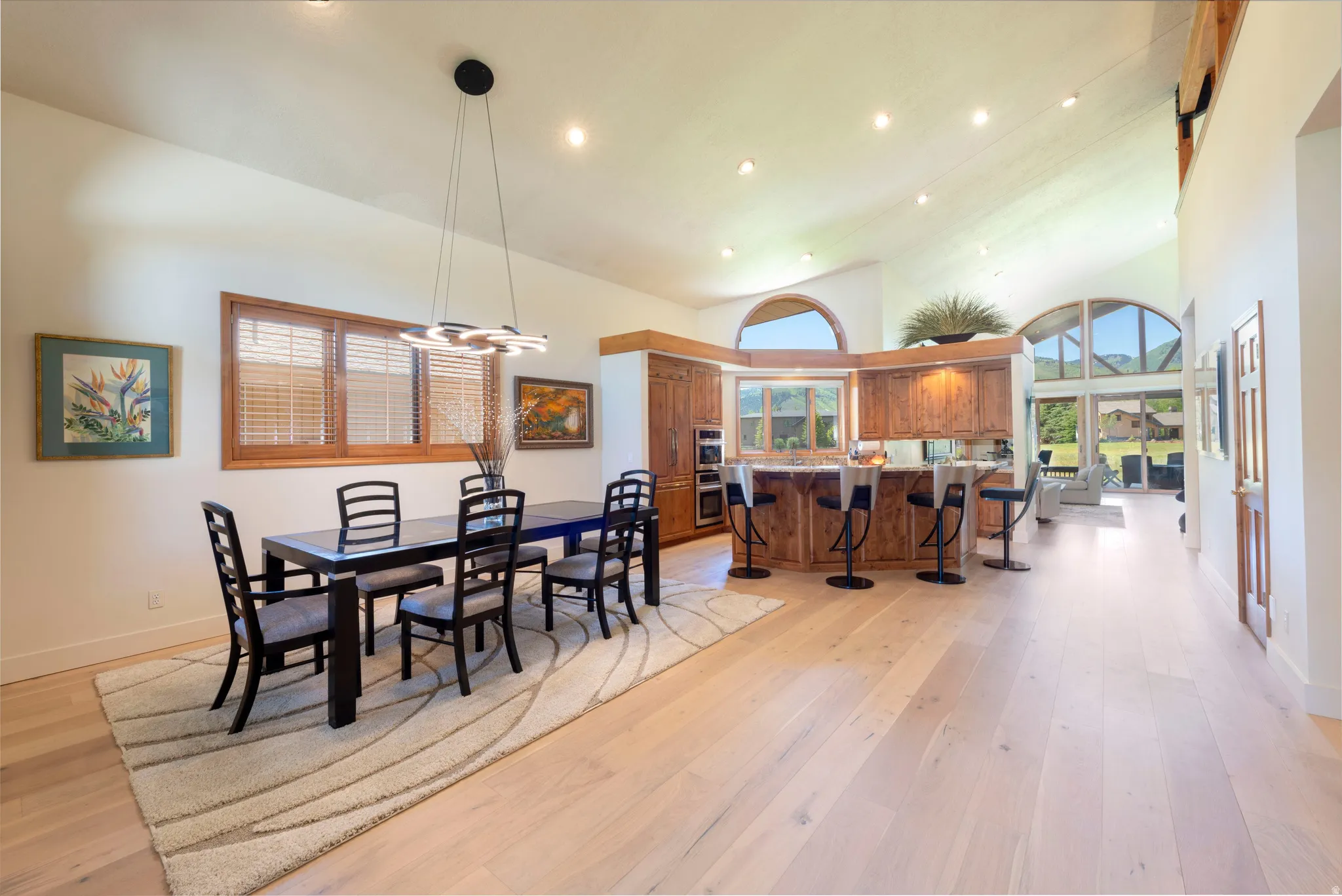 Hardwood flooring extending throughout an open-concept living area with vaulted ceilings and recessed lighting
