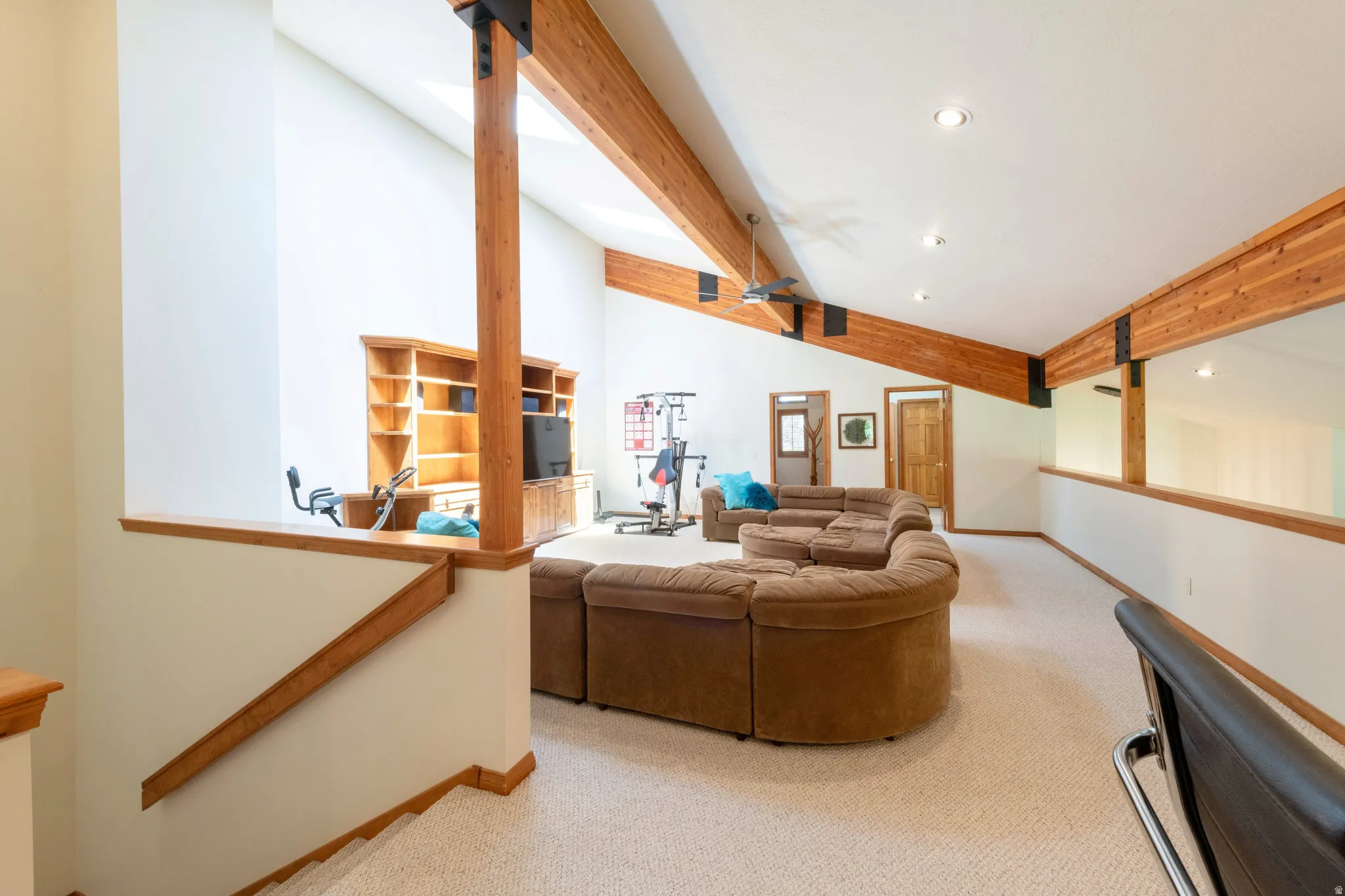Spacious upper-level area featuring exposed wood beams, vaulted ceilings, and recessed lighting