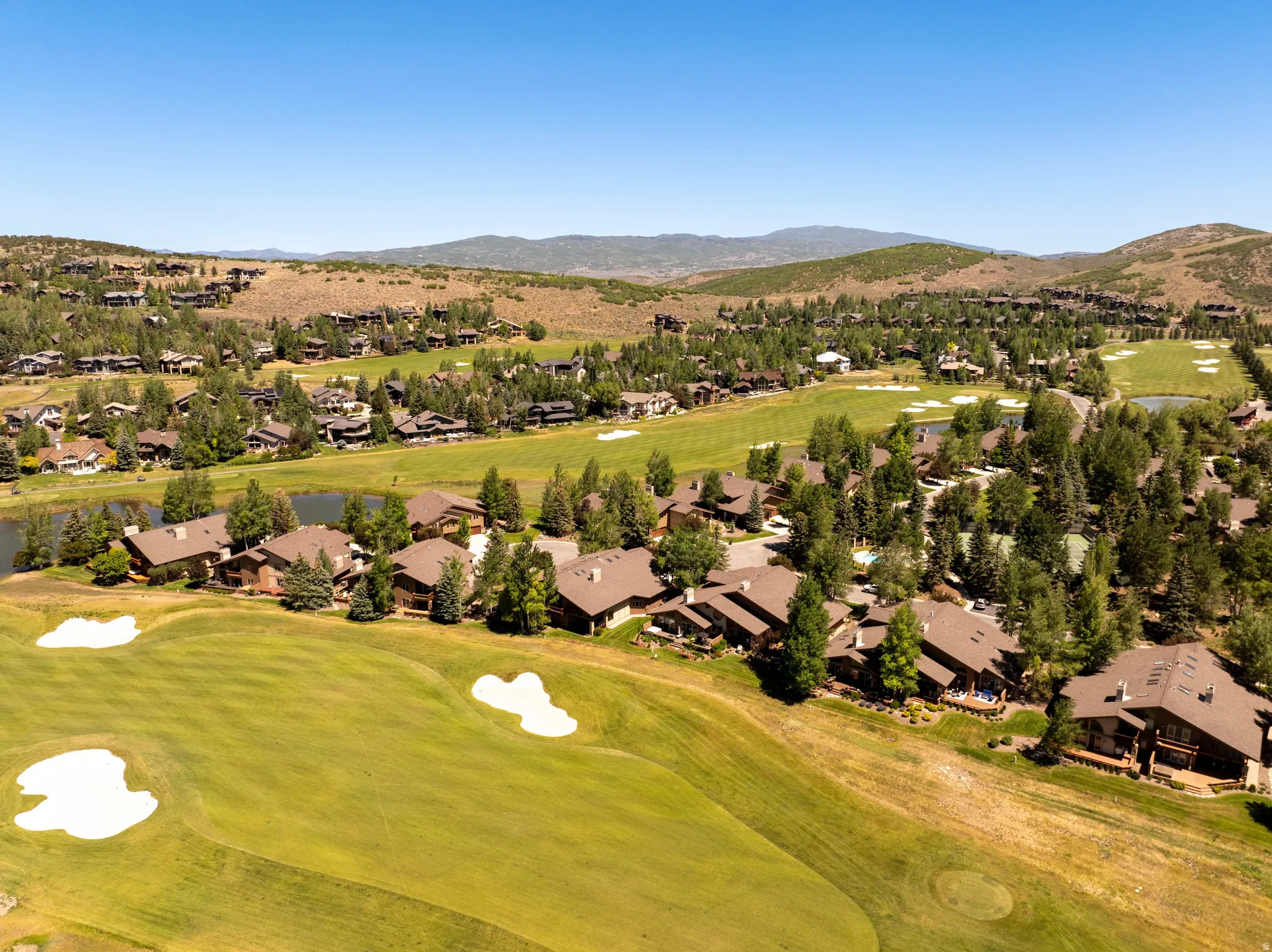 Aerial perspective showcasing properties bordering a golf course with sand traps and green fairways
