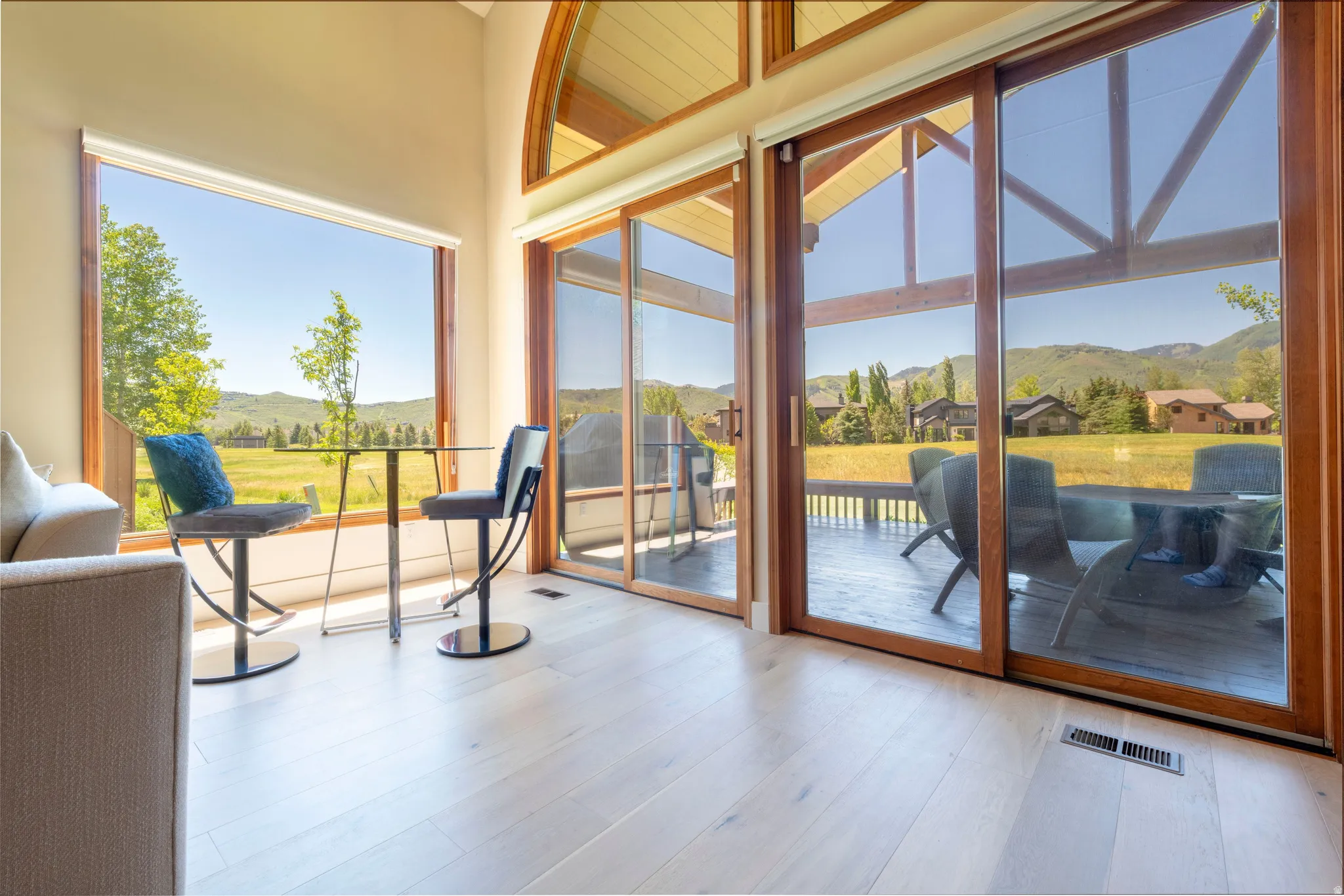Spacious interior featuring light wood-finish flooring, vaulted ceilings, and extensive natural wood-framed windows