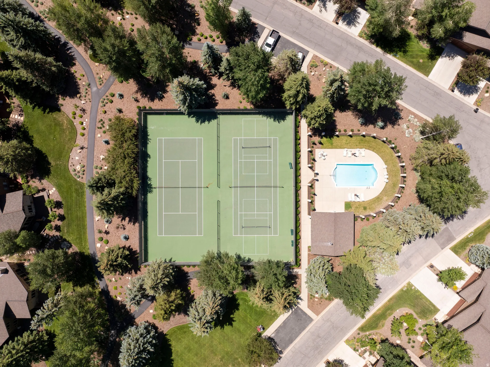 Community amenities featuring two tennis courts, an outdoor swimming pool, and extensive paved pathways surrounded by mature trees and landscaping