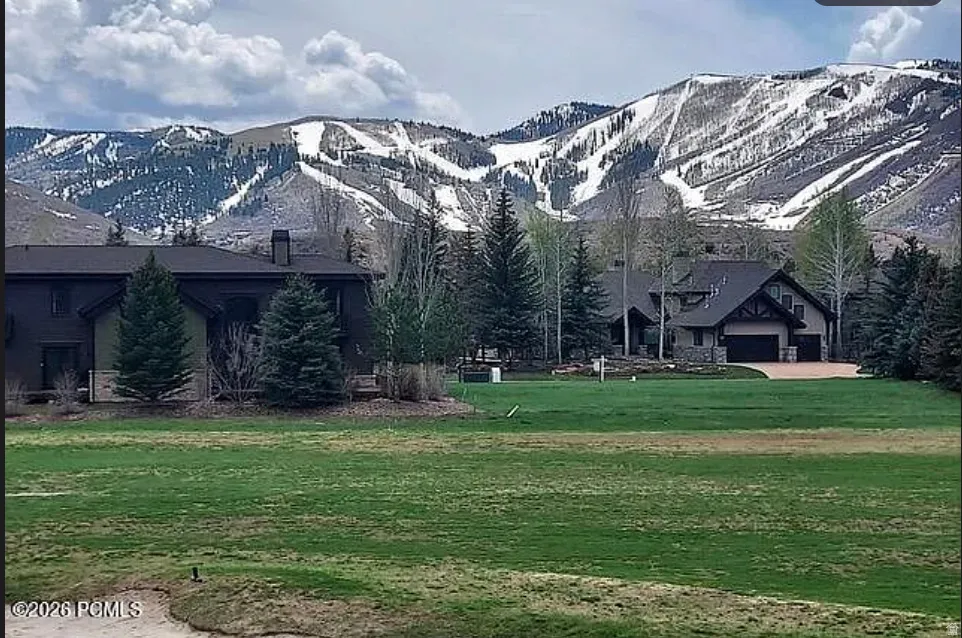 Expansive green lawn with mountain backdrop featuring snow-capped peaks