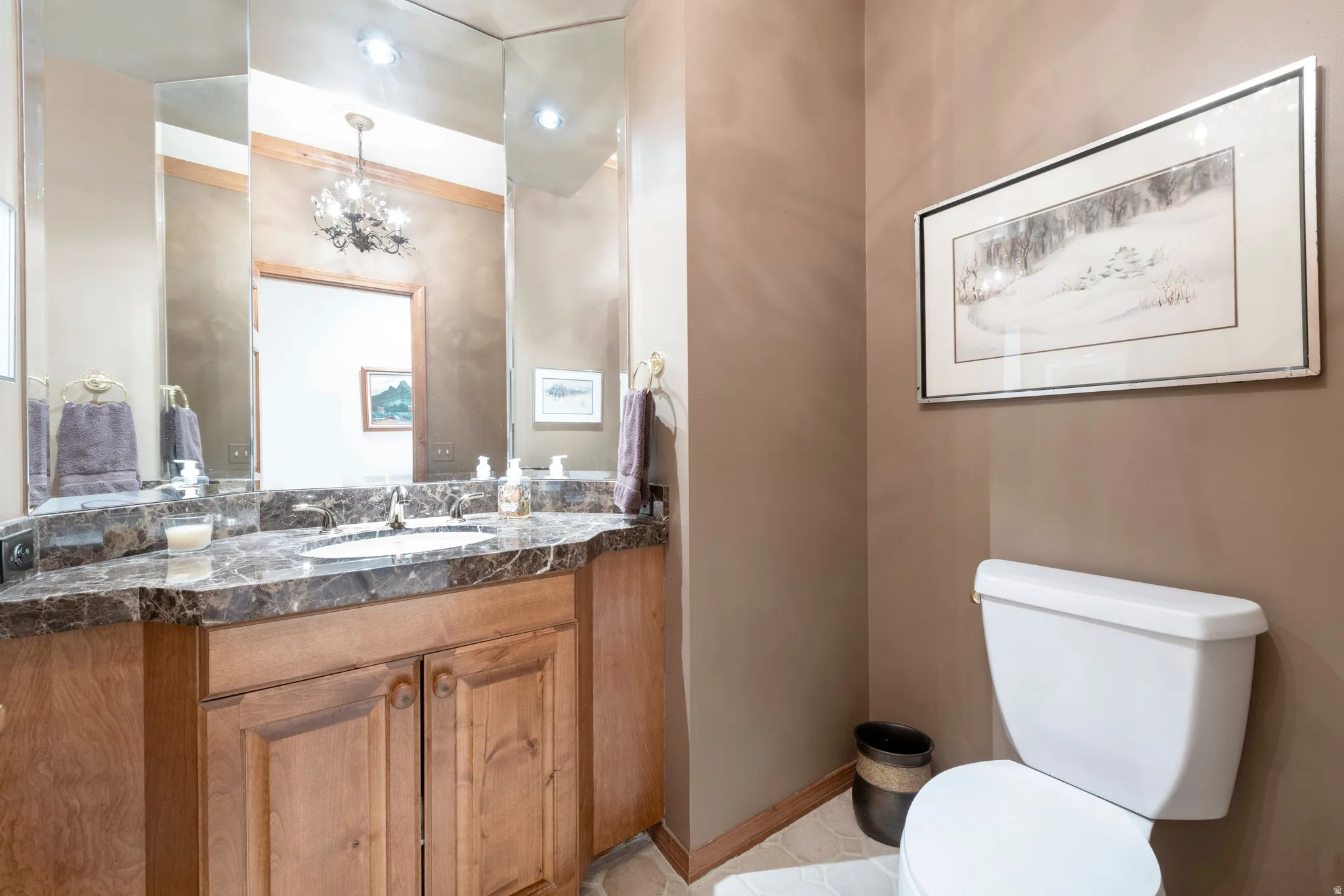 Bathroom vanity featuring a dark patterned countertop, integrated sink, and light wood cabinetry