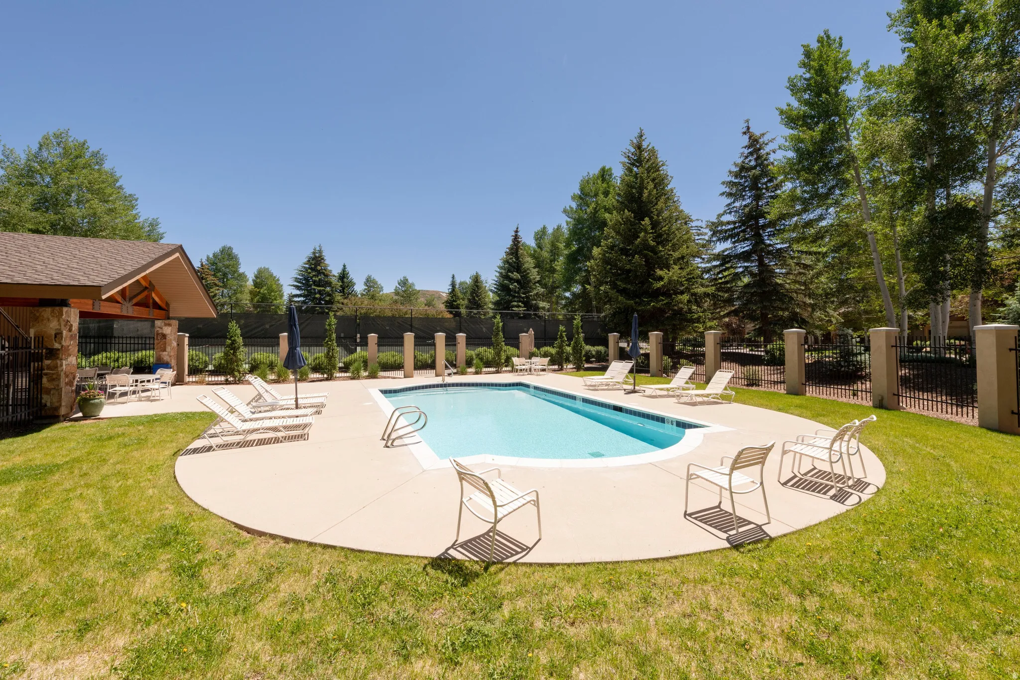 Outdoor swimming pool with a surrounding concrete deck, flanked by manicured green lawn