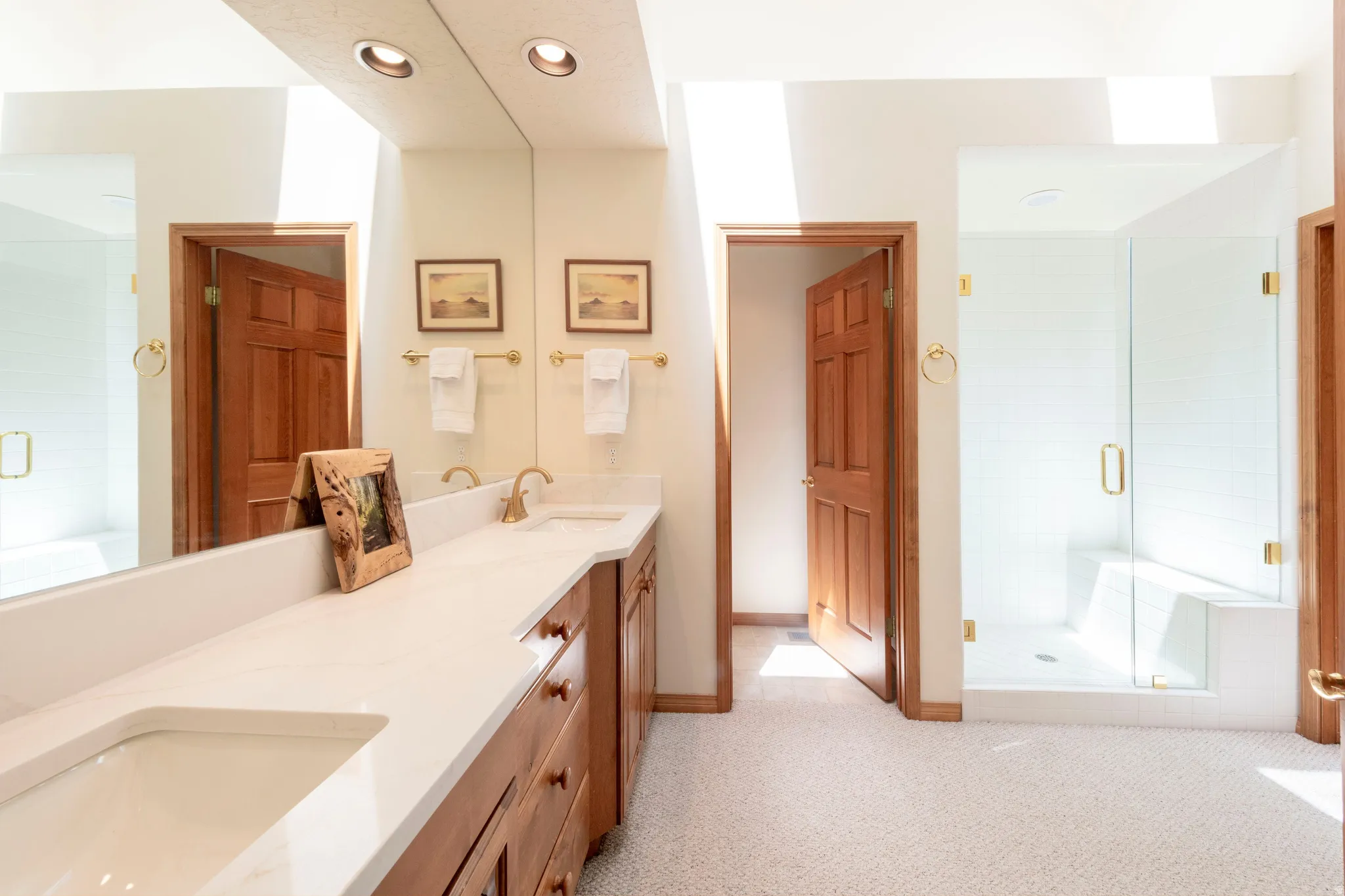 Dual vanity with integrated sinks and a white countertop, featuring brass-toned fixtures and wood cabinetry