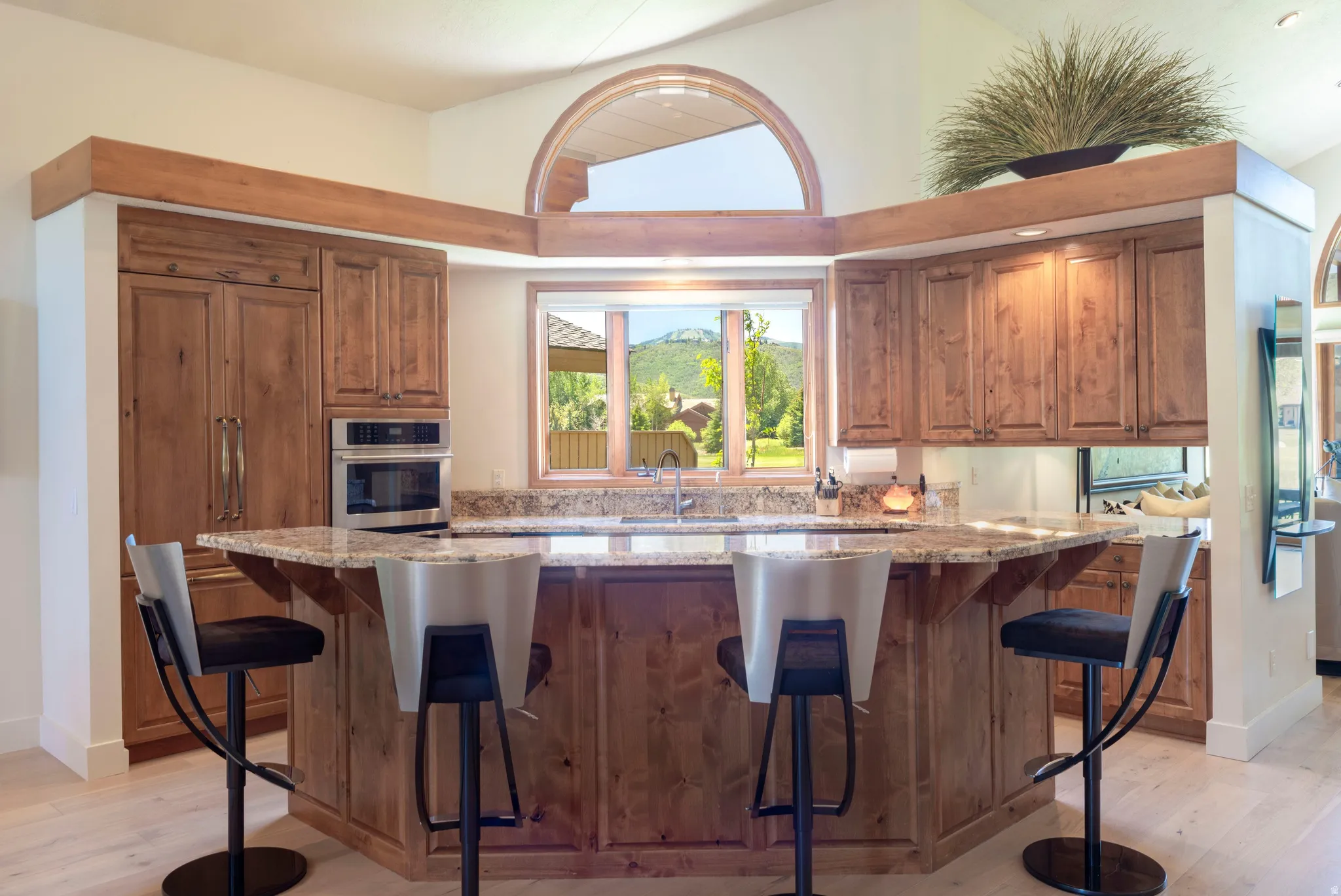 Kitchen featuring an expansive island with a granite countertop, integrated sink, and an arched window