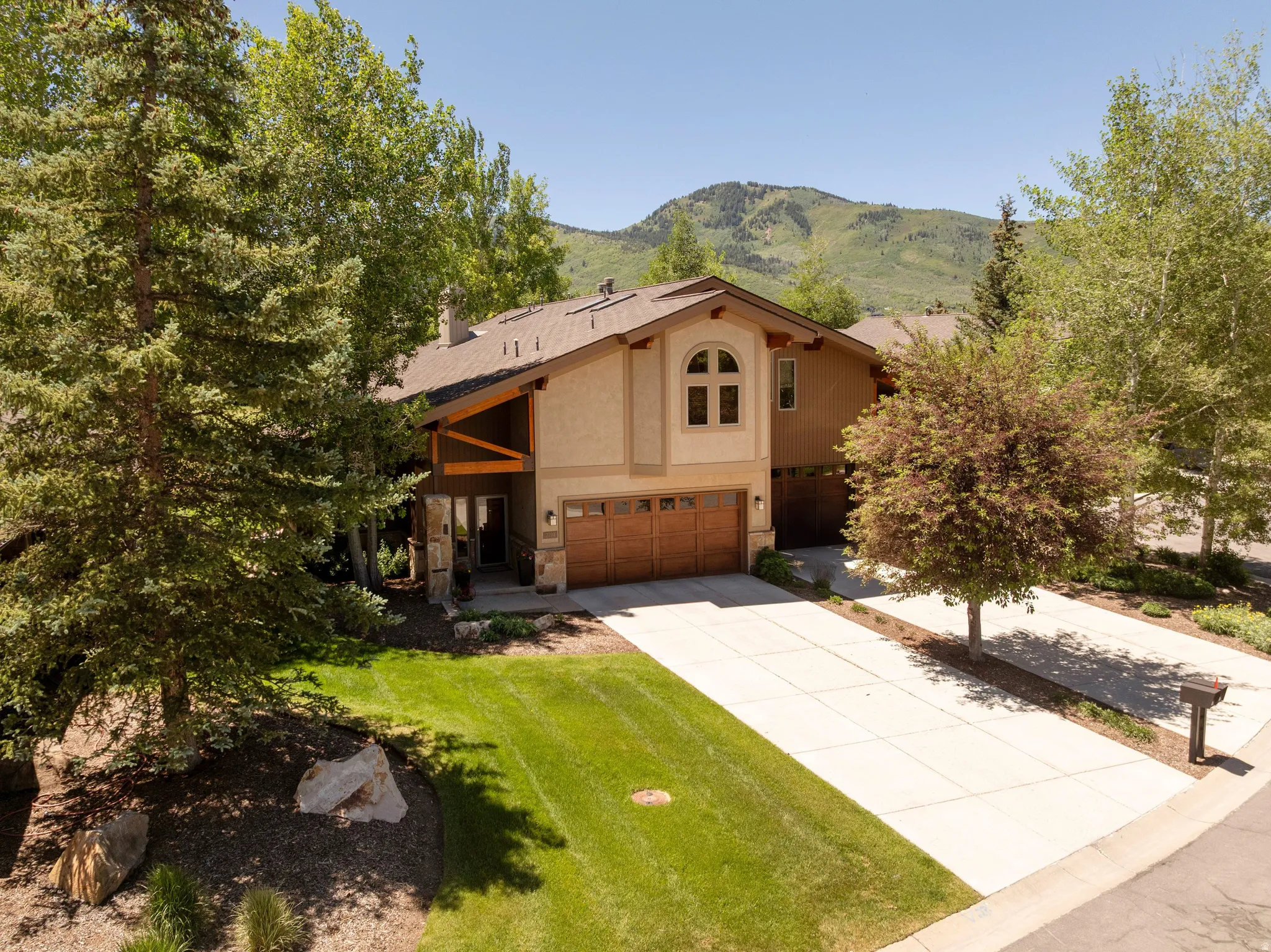 Stucco exterior home featuring a prominent arched window, a two-car garage with wood-finish doors, and a concrete driveway