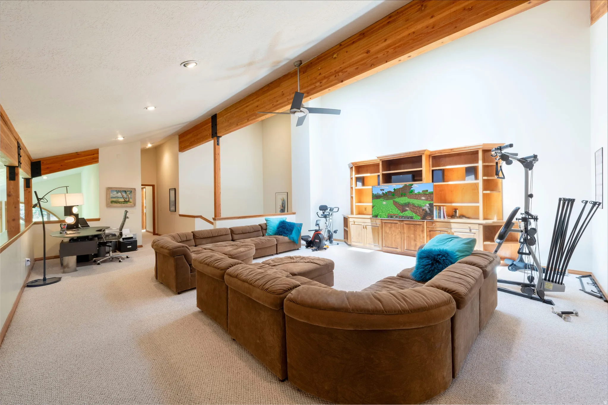 Open-concept living area with vaulted ceilings, exposed wood beams, a built-in entertainment center, recessed lighting, and soft carpeting