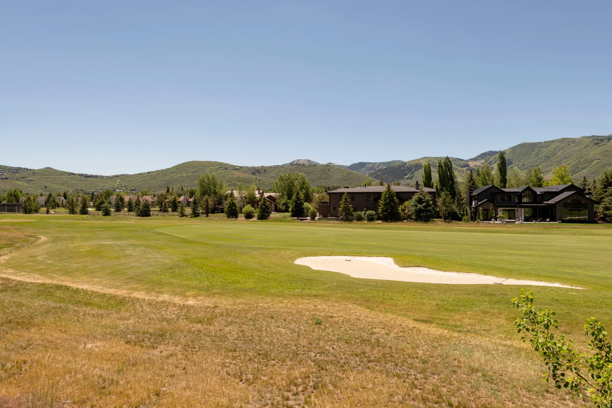 Expansive golf course setting featuring a sand trap, manicured fairways, and distant mountain backdrops