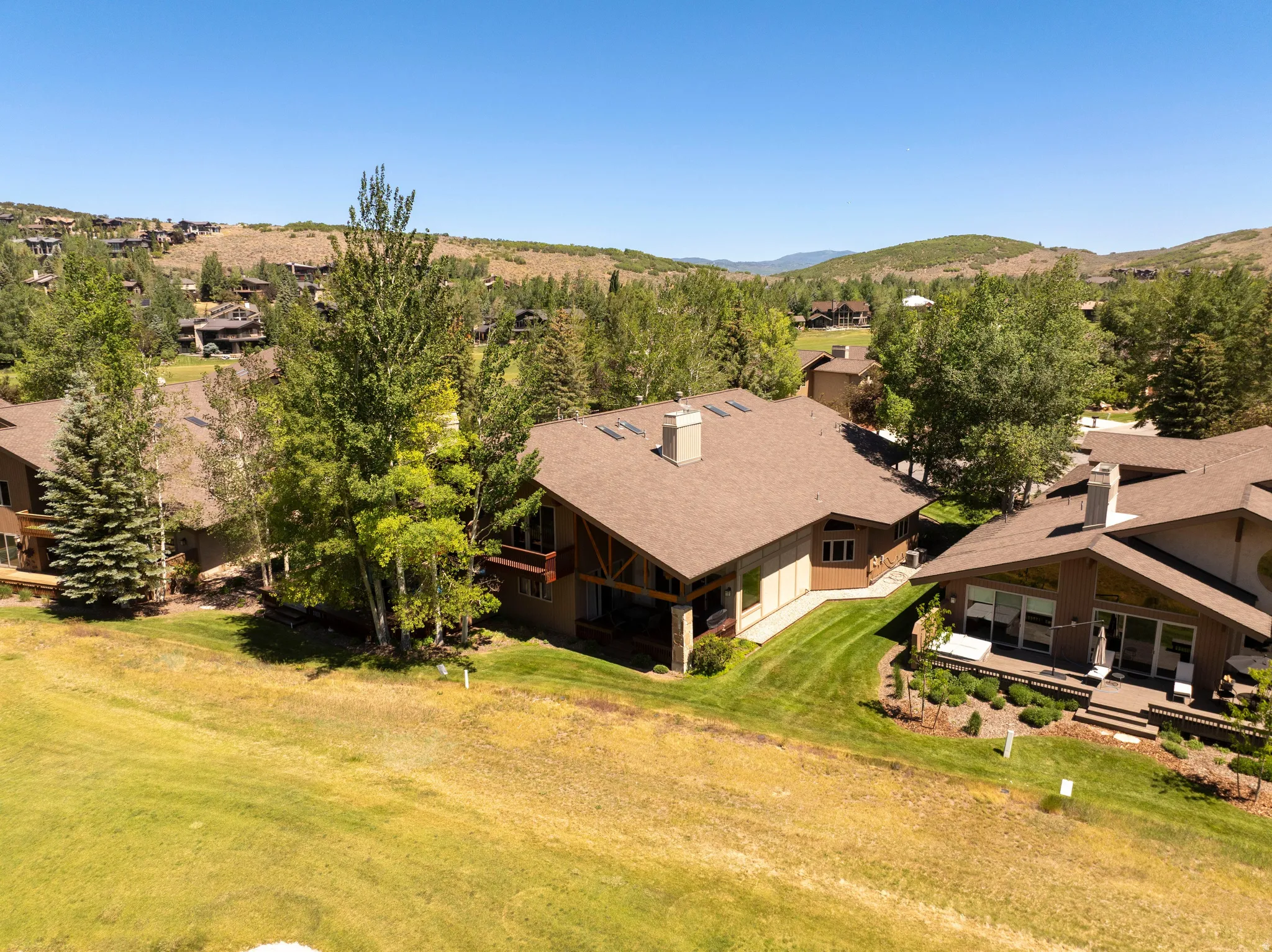 Sloped property featuring established trees and manicured lawn areas