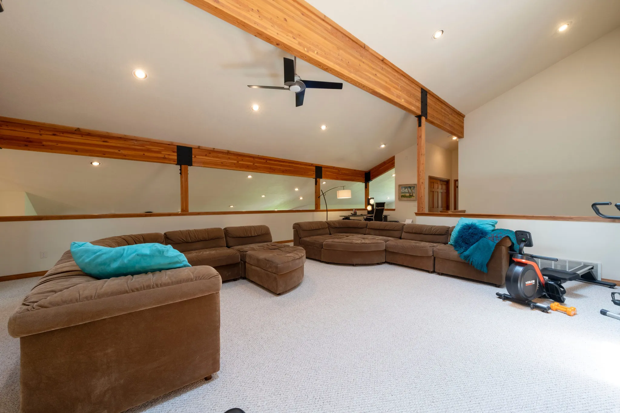 Lofted living area featuring vaulted ceilings with exposed wood beams, recessed lighting, and a ceiling fan