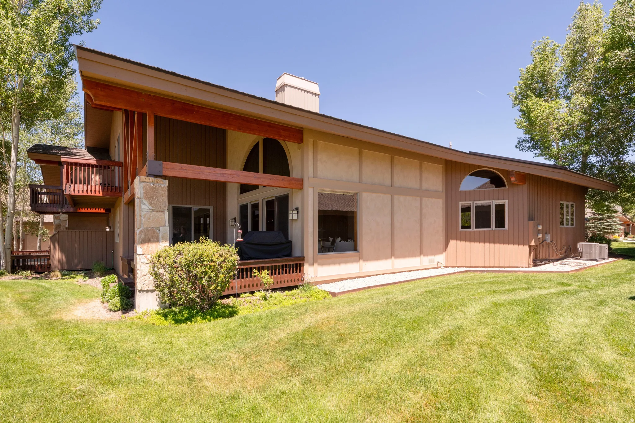 Wood-sided exterior featuring stone accents, an arched window, and a deck with railings