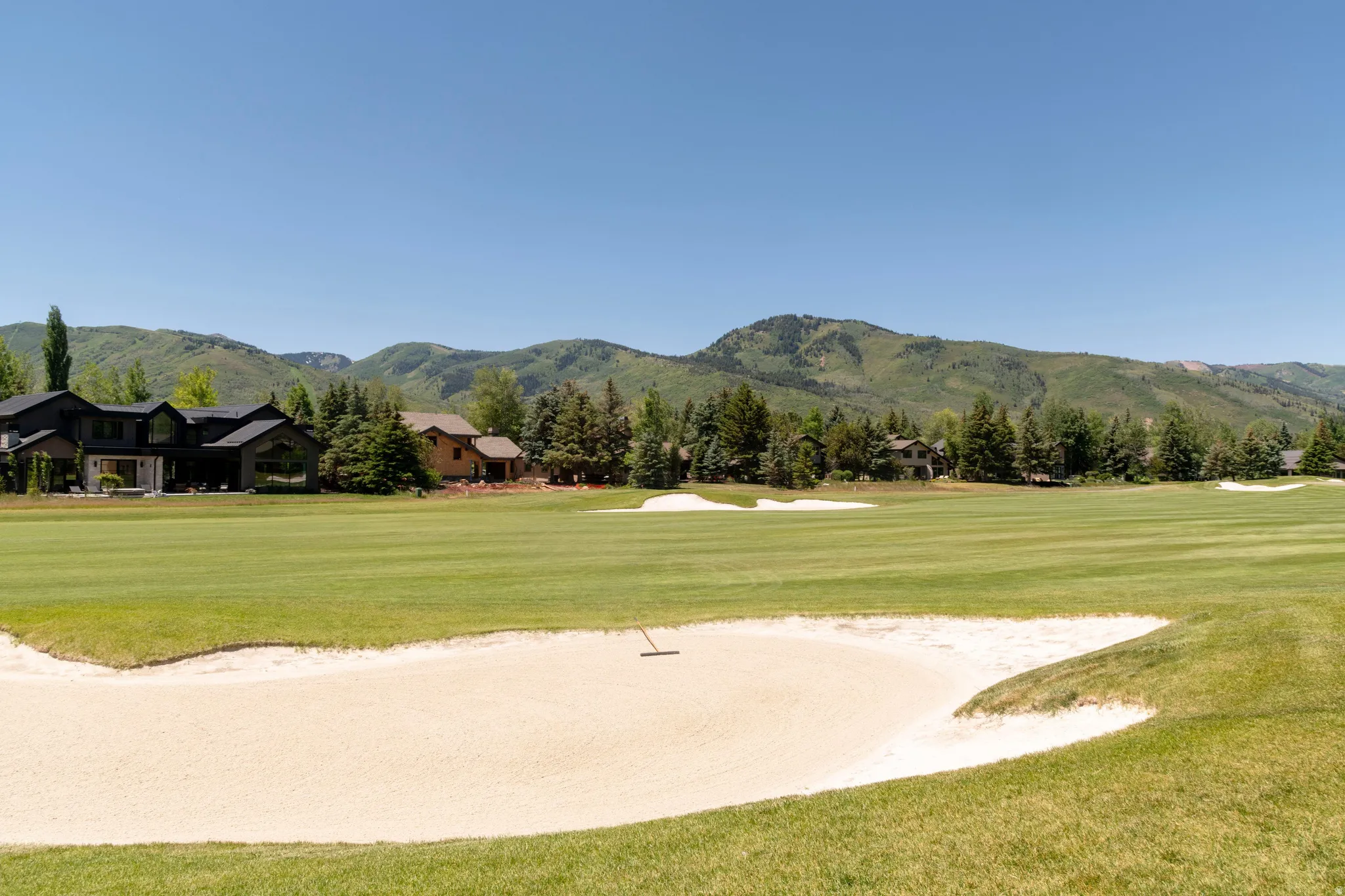 Expansive golf course setting featuring a sand trap, manicured fairways, and distant mountain scenery