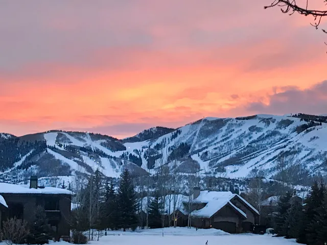 Snow-covered mountain range featuring ski runs under a vibrant sky