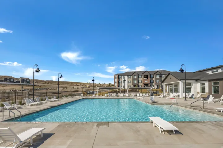 Expansive outdoor swimming pool with concrete decking, surrounding lounge areas, and decorative black lampposts