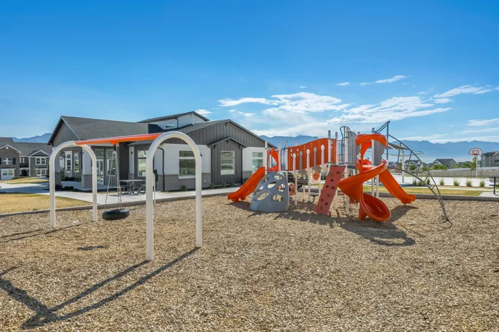 Dedicated recreational area featuring a modern playground structure with slides, climbing elements, and a tire swing