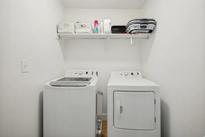 Dedicated laundry area featuring a top-load washing machine and a front-load electric dryer