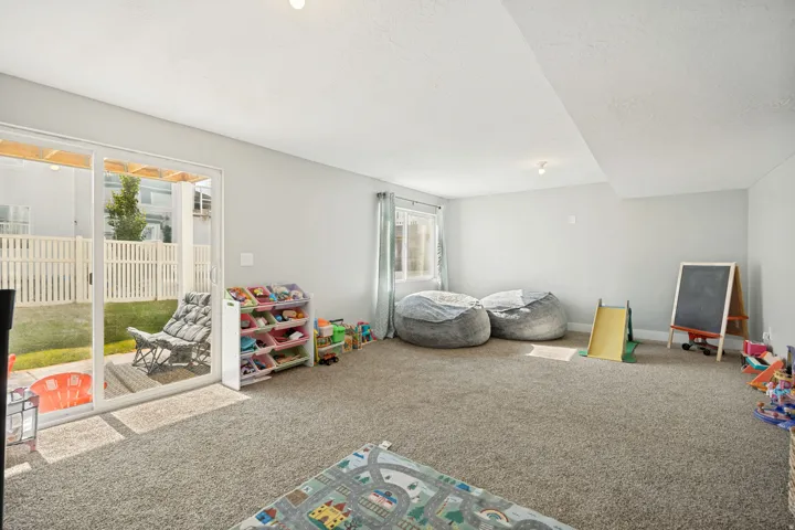 Carpeted room with a sliding glass door providing outdoor access to a fenced yard