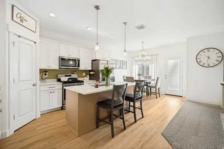 Modern kitchen featuring white cabinetry, stainless steel appliances, a center island with bar seating, and wood-finish flooring