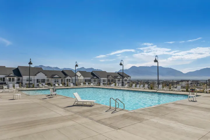 Expansive outdoor swimming pool with integrated shallow area, surrounded by a concrete deck and multiple lounge chairs