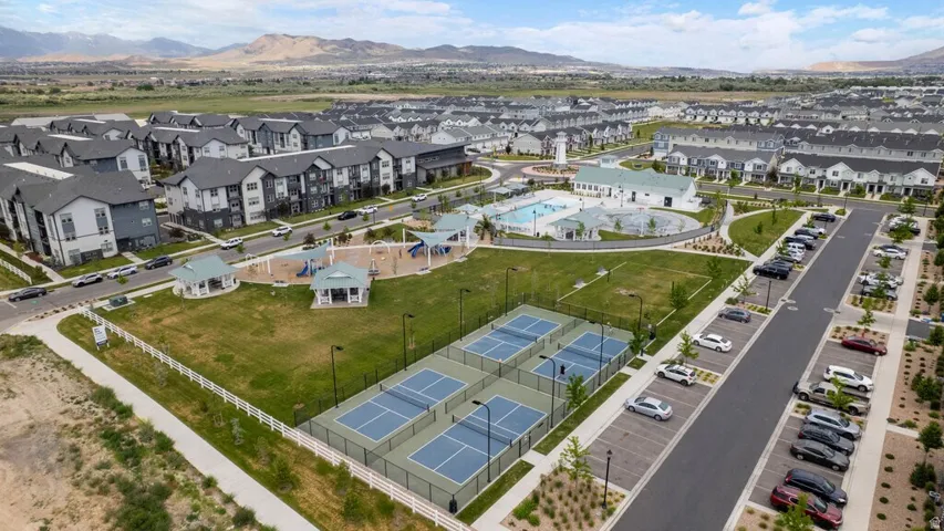 Expansive community green space featuring four pickleball courts, a playground with multiple structures, and two covered gazebos