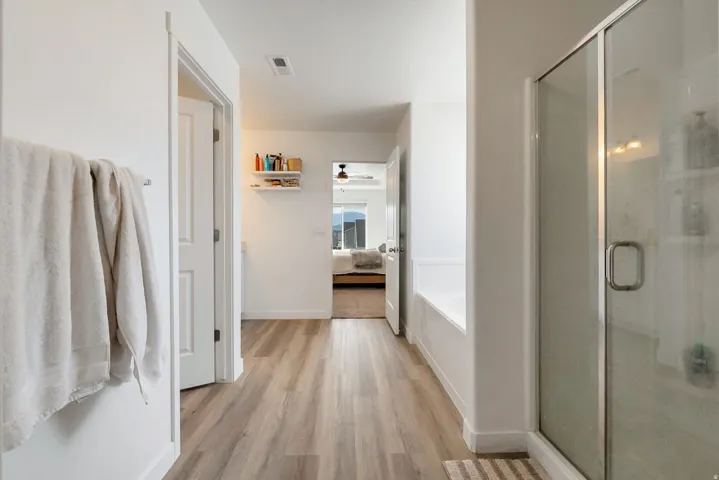 Contemporary bathroom featuring a glass-enclosed shower, built-in bathtub, and wood-finish flooring