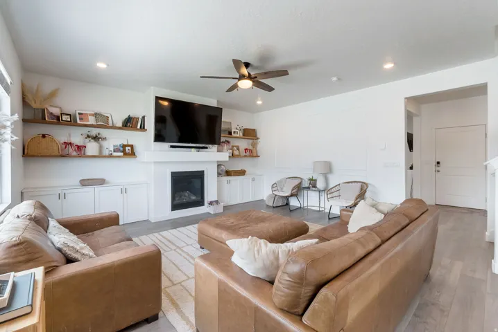 Living area featuring a central fireplace with a mantel, built-in lower cabinetry, and floating shelves