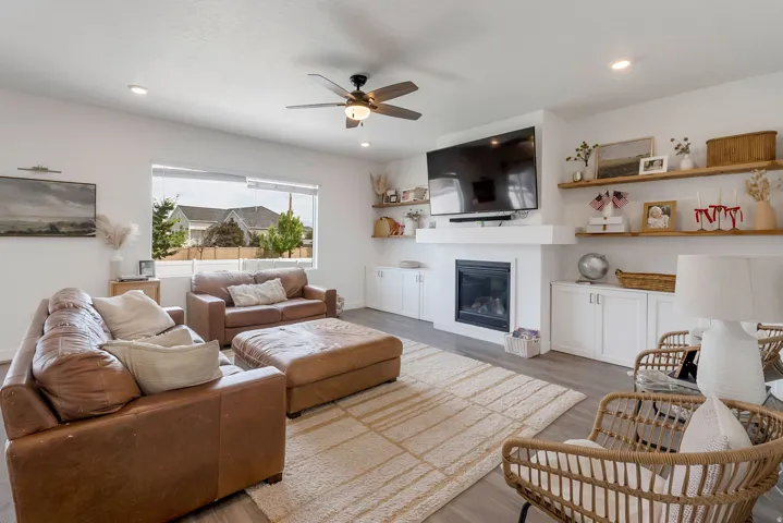 Spacious living area featuring light wood-finish flooring, a contemporary ceiling fan, and recessed lighting