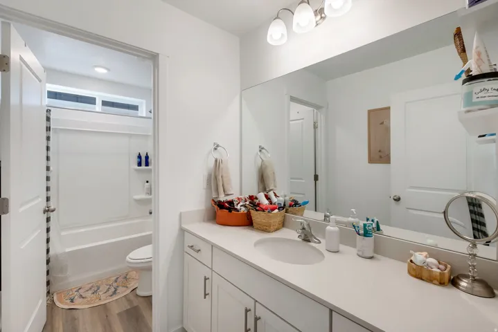 Bathroom featuring a single vanity with an integrated sink, a large wall-mounted mirror, and a three-light fixture