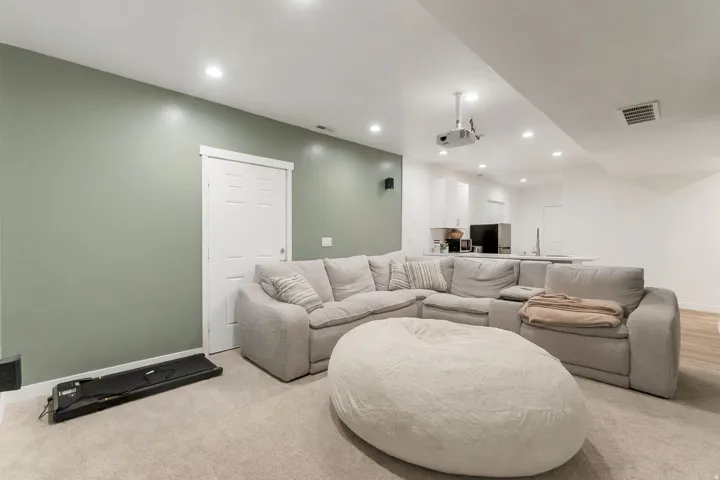 Open-concept living area with recessed lighting, green accent wall, and projector installation