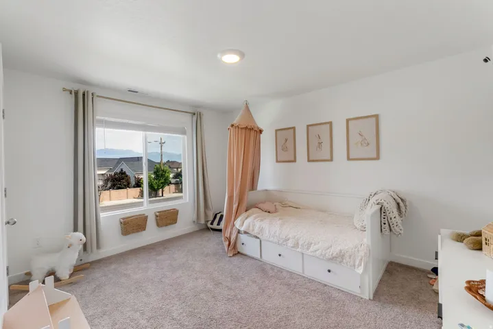 Light-filled room featuring a large window with white trim, recessed ceiling light, and neutral wall-to-wall carpeting