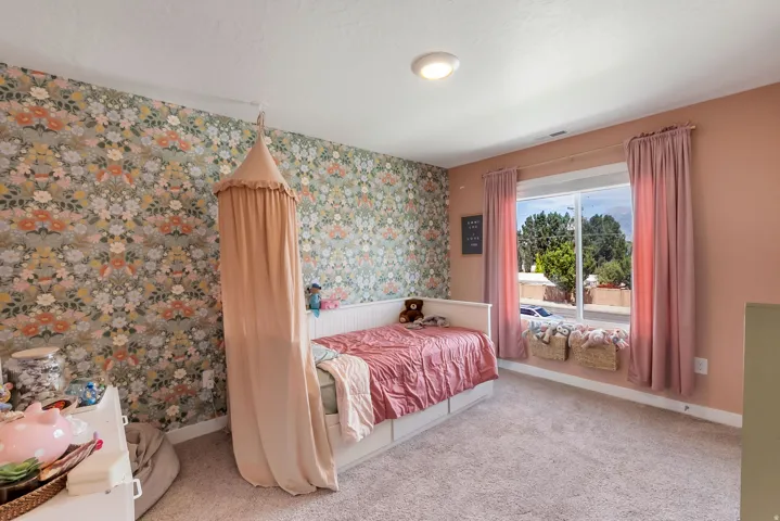 Bedroom featuring a floral accent wall and a large window