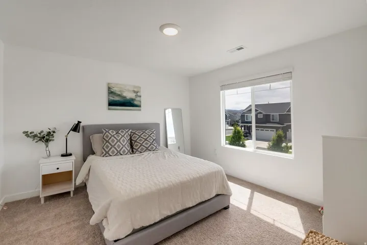 Bright room featuring a large window, plush carpet, and a flush-mount ceiling light