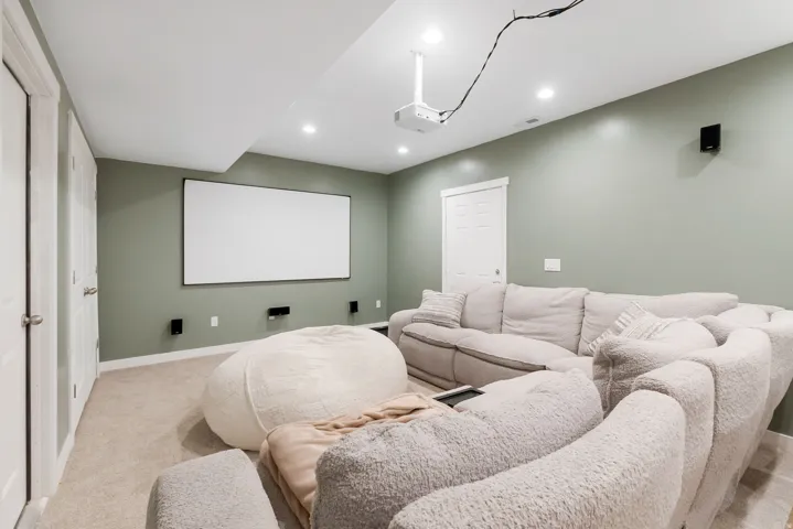 Dedicated media room featuring a large projection screen, ceiling-mounted projector, and integrated wall-mounted speakers