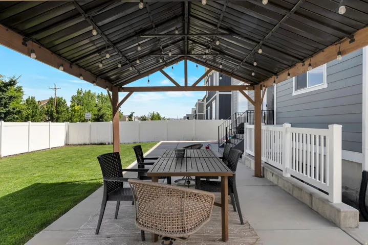Covered patio area featuring a slatted roof and string lights